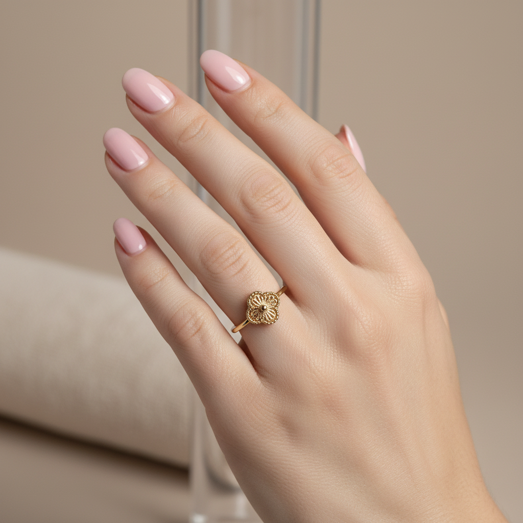 Anillo trébol en mano con uñas rosa