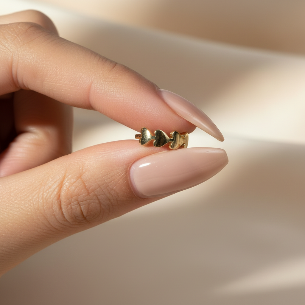 Arete de oro con corazones - Mano con uñas puntiagudas