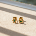 Aretes de flores con piedra verde fondo beige sin texto