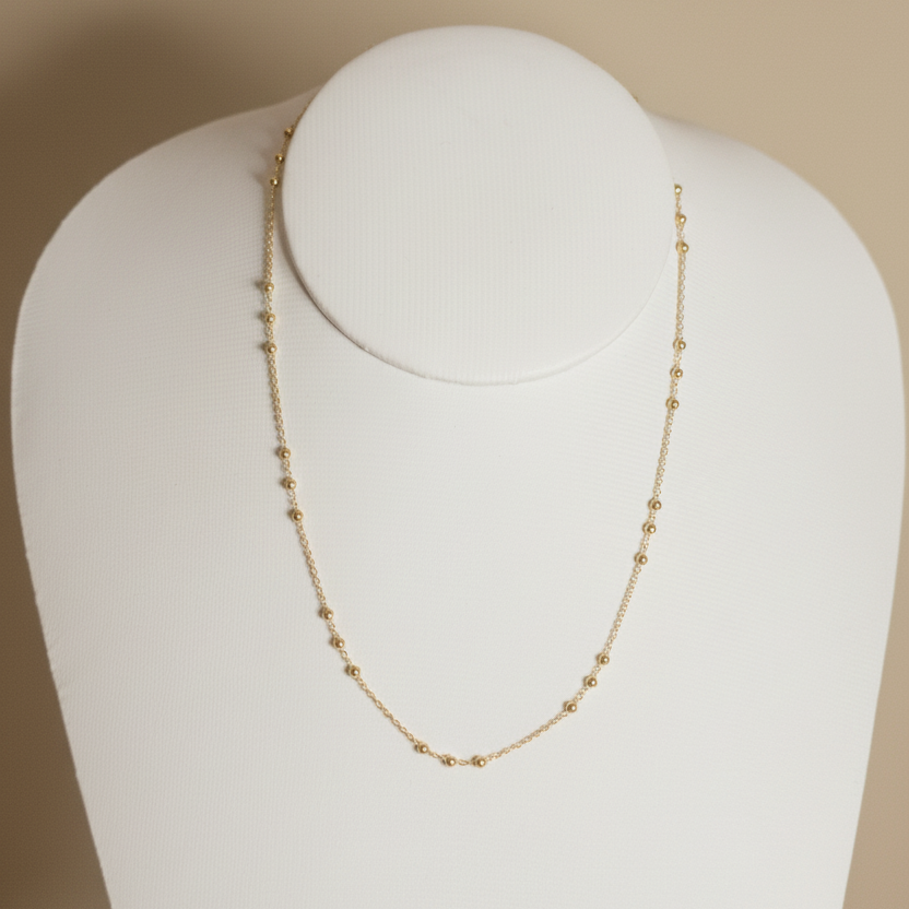 Cadena de bolitas en cuello blanco