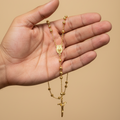 Rosario oro amarillo en mano de hombre