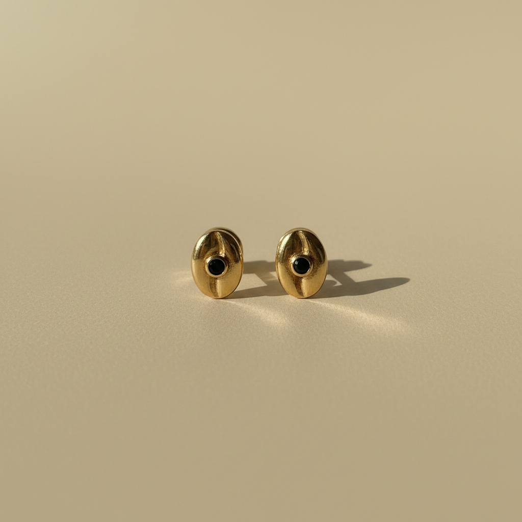 Topitos ovalados en oro con piedra negra fondo beige plano